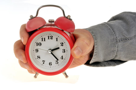 Alarm clock held in hand on white backgroundの写真素材