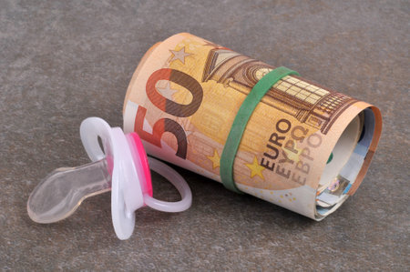 Pacifier with a wad of euro banknotes close-up on a gray backgroundの写真素材