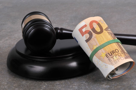 Court fees concept with with a judge gavel and a wad of euro banknotes close up on a gray backgroundの写真素材
