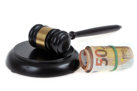 Court fees concept with with a judge gavel and a wad of euro banknotes close up on a white backgroundの写真素材