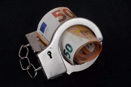 Euro banknotes with handcuffs close-up on black backgroundの写真素材