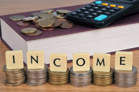 Income concept with stacks of coins and alphabet lettersの写真素材