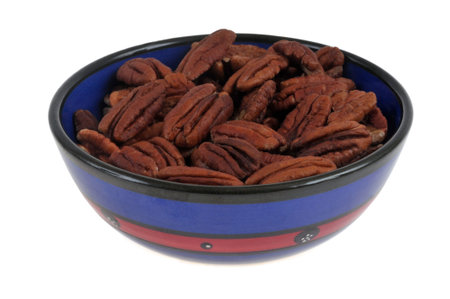 Ramekin of pecan nuts close up on white background