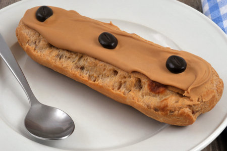 A coffee eclair in a plate with a spoon close-up
