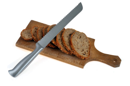 Sliced seed bread on a wooden cutting board with a knife on white backgroundの写真素材
