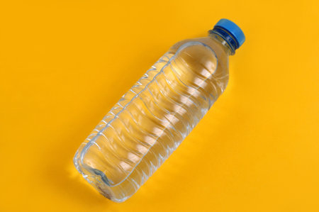 plastic mineral water bottle close up on yellow backgroundの写真素材