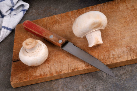 Button mushrooms with a knife on a cutting board close-up