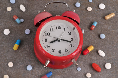 Assortment of medicines and alarm clock close-up on gray background
