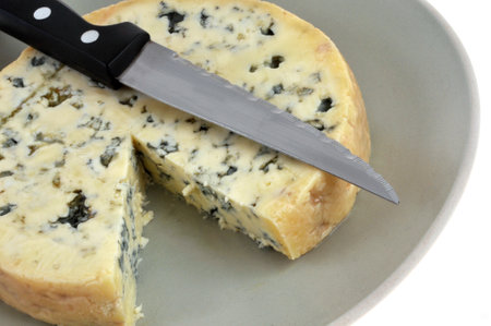 Fourme d'Ambert cheese cut into a plate with a knife close-upの写真素材