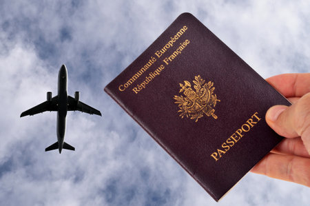 European passport in hand with a plane in the sky in the backgroundの写真素材