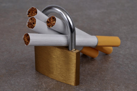 Blonde cigarettes with filter in a padlock close-up on gray backgroundの写真素材