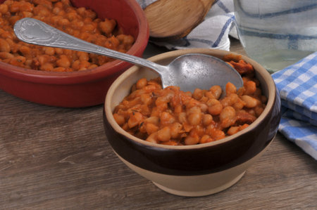 Bowl of white beans in tomato sauce with a spoon close-upの写真素材