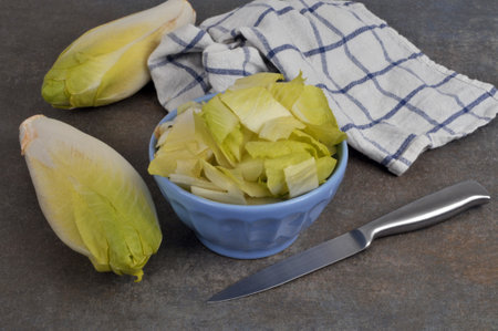 Bowl of endives cut with a knife and whole endives close-upの写真素材