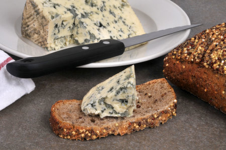 Piece of Auvergne blue cheese on a slice of seeded bread with a knife close-up