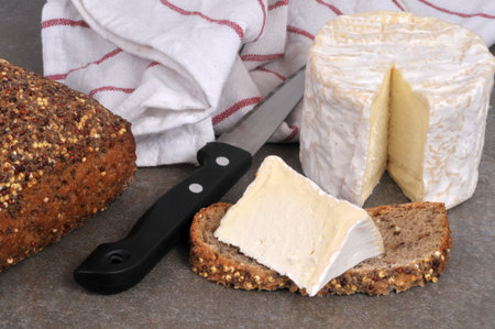 Piece of Chaource on a slice of seeded bread with a knife close-up