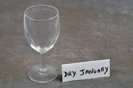 Dry January concept with an empty wine glass and text on a card on a gray backgroundの写真素材