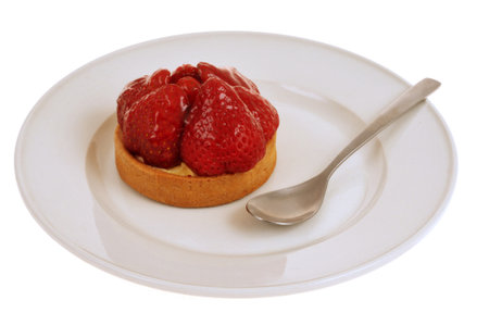 Strawberry tartlet in a plate with a spoon closeup isolated on a white backgroundの写真素材