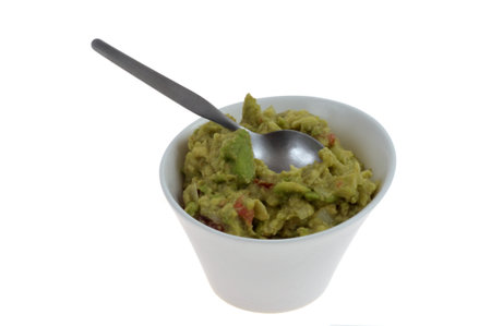 Ramekin of homemade guacamole with spoon close-up on white backgroundの写真素材