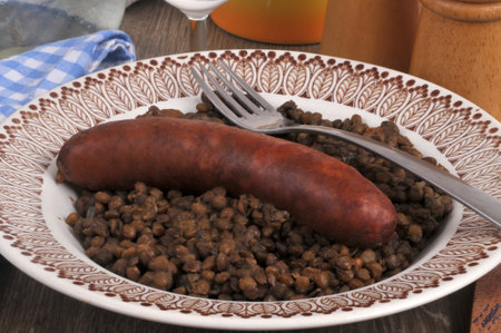 Plate of sausage and lentils served with a fork closeupの写真素材