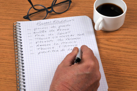 Writing my New Year's resolutions in French on a spiral notebook with a pen closeupの写真素材