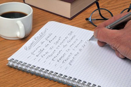 Writing my New Year's resolutions in French on a spiral notebook with a pen closeupの写真素材