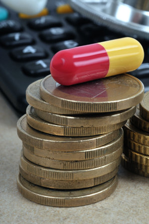 Yellow and red capsule placed on a pile of euro coinsの写真素材