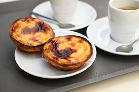 PastÃ©is de nata in a saucer next to cups of espressoの写真素材