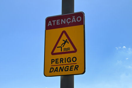 Sign indicating danger in Portuguese and Englishの写真素材