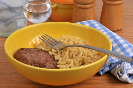 Plate with minced steak accompanied by pasta with a fork in closeupの写真素材