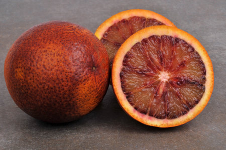 Whole blood orange and halved blood orange close-up isolated on gray backgroundの写真素材