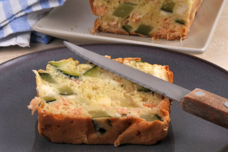 Slice of homemade savory feta and vegetable cake on a plate with a knife close-upの写真素材