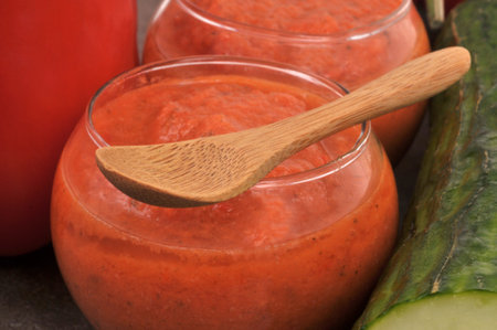 Homemade gazpacho glass with wooden spoon closeup on backgroundの写真素材