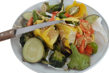 Plate of assorted vegetable peels piled up with a knife close-up on a white backgroundの写真素材