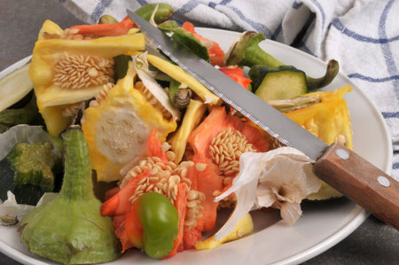 Plate of assorted vegetable peels piled up with a knife closeup on backgroundの写真素材