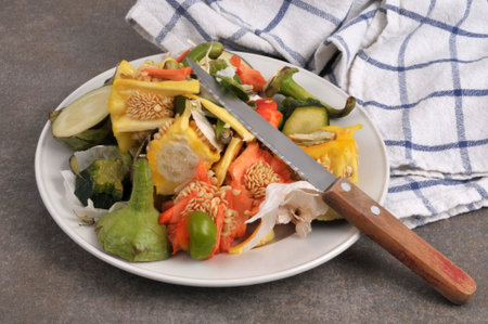 Plate of assorted vegetable peels piled up with a knife closeup on a gray backgroundの写真素材