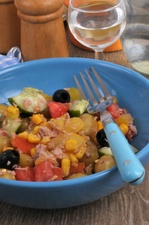 Homemade mixed salad served on a plate with a fork and a glass of waterの写真素材