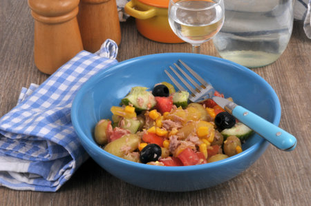 Homemade mixed salad served on a plate with a fork and a glass of waterの写真素材