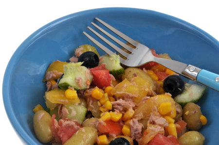 Homemade mixed salad served on a plate with a fork close-up on a white backgroundの写真素材