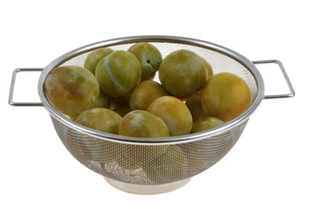 Close-up of a colander of greengage plums isolated on a white backgroundの写真素材