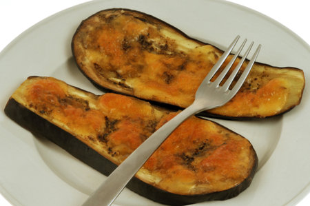 Eggplant slices cooked with melted cheese on a plate with a fork close-up on a white backgroundの写真素材