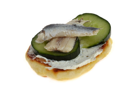 Blini appetizer with cucumber slices and herring fillets in close-up isolated on white backgroundの写真素材