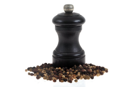 Black pepper mill with peppercorns in close-up on a white backgroundの写真素材