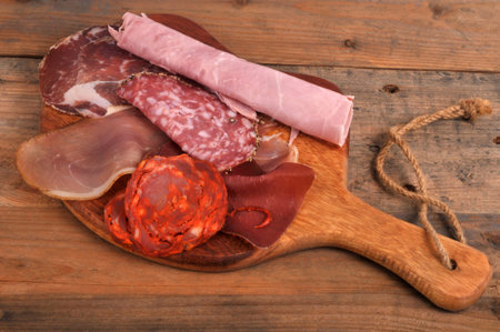 Assortment of cold cuts on a wooden cutting board closeup