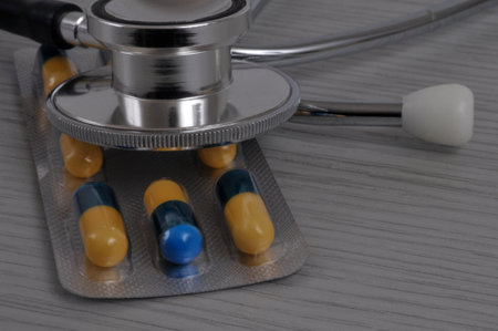 Blister pack of yellow and blue capsules with a close-up of a stethoscopeの写真素材