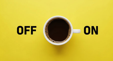 A white cup of black coffee is placed between the words "OFF" and "ON" on a bright yellow background.の素材