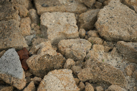 A detailed close-up of weathered, rough broken concrete pieces and construction rubble forming a...