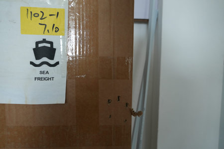 A close-up view of a cardboard box with a white label indicating SEA FREIGHT and a yellow sticker...