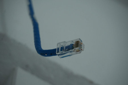 A blue Ethernet cable with a clear plastic connector is shown in a close-up view, with the cable...