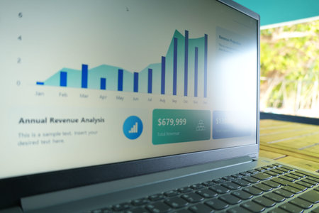 A laptop screen displays an annual revenue analysis with bar graphs, total revenue, and expenses,...
