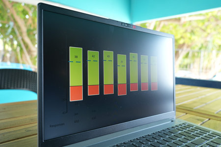 A laptop shows a bar graph with green and red bars on its screen, placed on a wooden table outside...